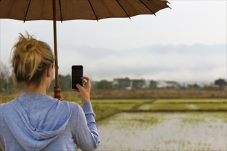 Caucasian woman photographing rural rice fields