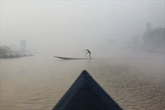 Asian woman rowing canoe on rural lake