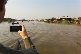 Caucasian man photographing with cell phone on rural river