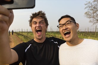 Men taking selfie with cell phone in vineyard