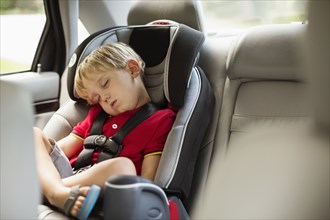 Caucasian boy napping in car seat