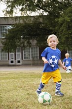 Caucasian boy playing soccer in field