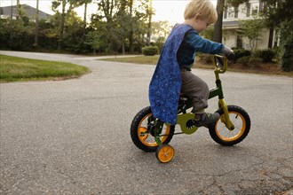 Caucasian boy riding bicycle with training wheels