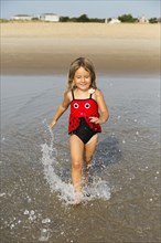 Mixed race girl splashing in waves on beach