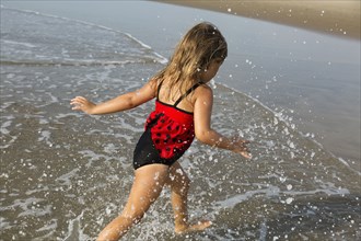Mixed race girl splashing in waves on beach