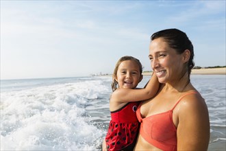 Mother holding daughter on beach