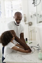 Boy helping father shave in bathroom