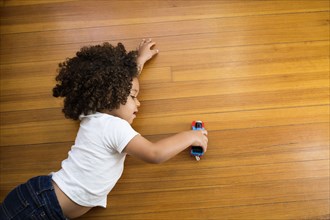 Mixed race boy playing with toy car on floor