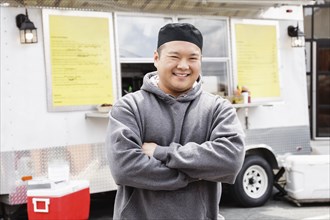 Proud Asian man standing at food truck