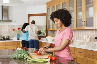 Black woman chopping tomato in kitchen