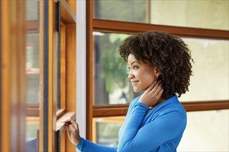 Smiling Black woman looking out window