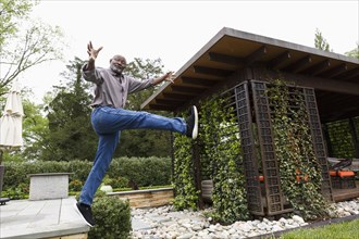 Black man jumping mid-air from bench in garden