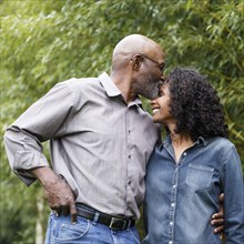 Black man kissing wife on forehead outdoors