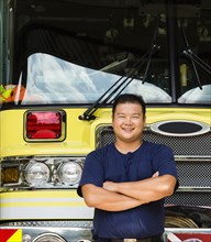 Smiling Chinese fireman posing with fire truck