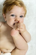 Caucasian baby boy biting foot