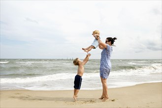 Caucasian mother and sons playing at beach