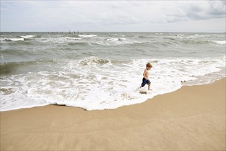Caucasian boy running in waves at beach
