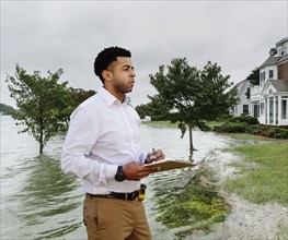 Black insurance adjuster examining flooding damage to house