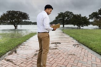 Black insurance adjuster examining flooding damage