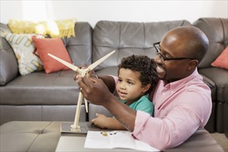 Father and son building model windmill in livingroom