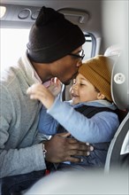 Father kissing son in car seat on forehead