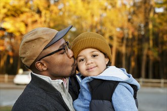 Father kissing son on cheek in park