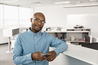 Smiling African American man texting on cell phone in office