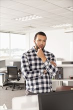 Pensive Mixed Race man standing in office