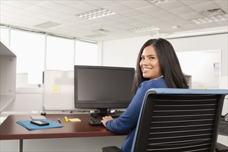 Smiling Pacific Islander woman using computer in office