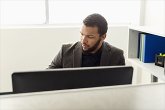 Mixed Race man using computer in office