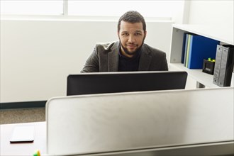 Smiling Mixed Race man using computer in office