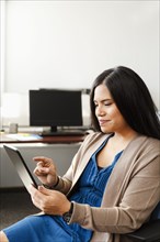 Pacific Islander woman using digital tablet in office