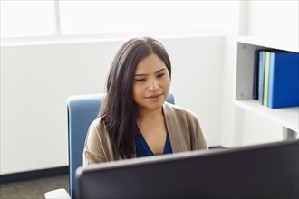 Pacific Islander woman using computer in office