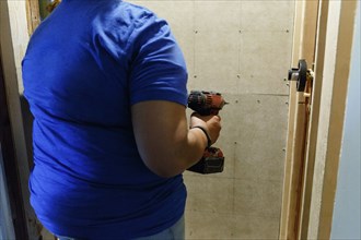 Black woman holding drill near wall