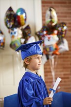 Caucasian boy wearing graduation robe holding diploma