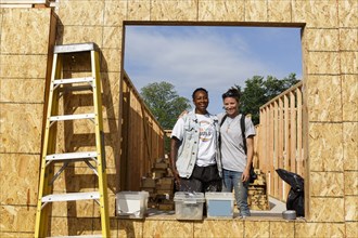 Portrait of volunteers behind window frame at construction site