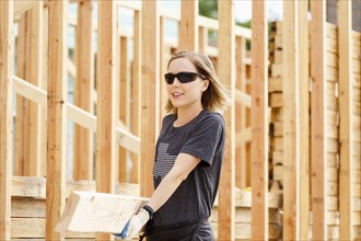 Caucasian woman carrying lumber at construction site