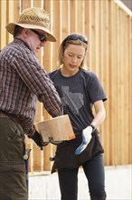 Caucasian man and woman carrying lumber at construction site