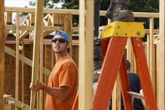 Caucasian man lifting lumber at construction site