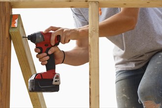 Caucasian woman drilling lumber at construction site
