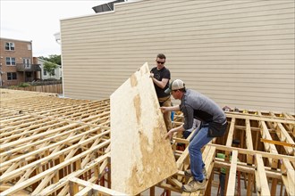 Caucasian men carrying plywood at construction site