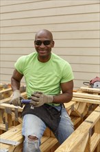 Black man posing with hammer at construction site