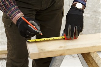 Caucasian man measuring lumber