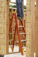 Legs of Caucasian man on ladder at construction site