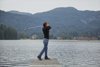 Caucasian woman golfing into lake