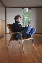 Caucasian woman using cell phone in armchair