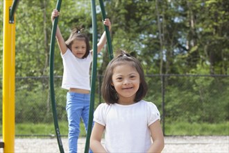 Mixed race Down syndrome girls smiling on playground