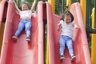 Mixed race Down syndrome girls playing on slides