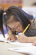 Mixed race Down syndrome student writing in workbook