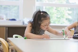 Mixed race Down syndrome students drawing in class